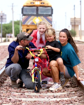 December 12, 2000. Nikki Webster visits the three whole residents from SA outback town Cook, Bruce and Michelle Hutchinson and son Brody (4yrs) who was presented with a new bike.
